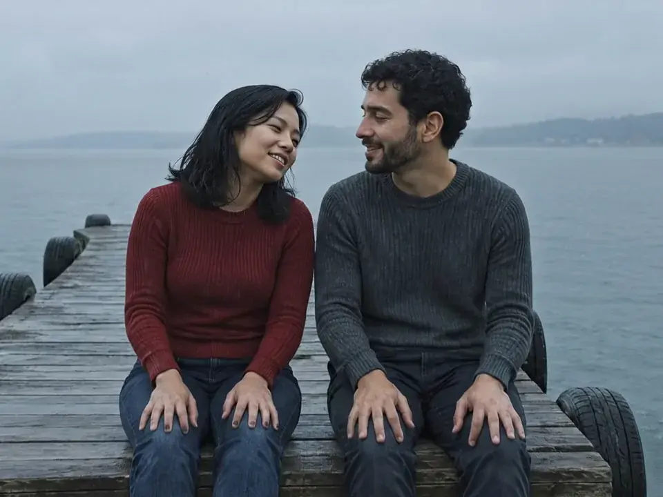 Two friends laughing on a pier on a grey rainy day