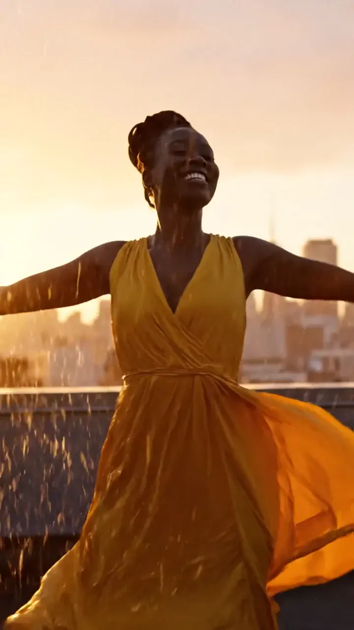 Woman in a yellow dress dancing on a rooftop in the rain